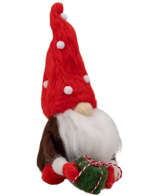 Plys jule-nissefigur med høj rød hue, hvidt skæg, brun krop og røde vanter, holder en grøn og rød gave med snor. Dekorativ julepynt.