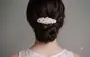 Elegant hårspænde med hvide perler, fastgjort til en flettet opstilling. Perfekt til formelle lejligheder, giver et sofistikeret look. Båret med blondekjole.