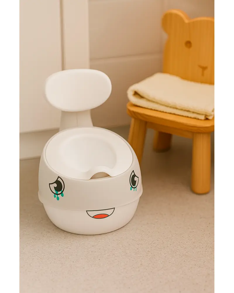 Vit plastpotta med leende tecknat ansikte, hög ryggstöd för stöd, lämplig för småbarn. Står bredvid en björnformad trästol med vikta handdukar.