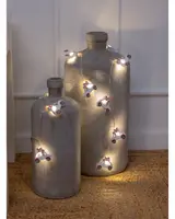 Lyskæde med hvide papirs juletræer og stjerner, der udsender et varmt skær. Dekorativ, batteridrevet, perfekt til julepynt. Leveres med rustik trækasse.