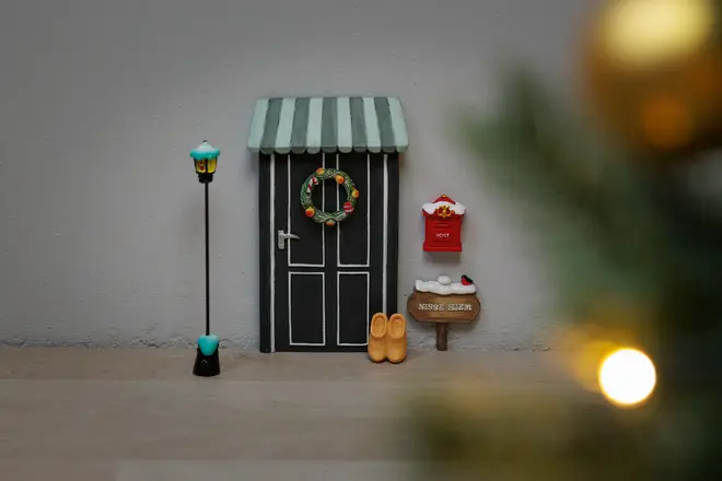 Miniature juledør med stribet markise, krans, sort lygtepæl, rød postkasse, træsko, skilt og små tilbehør. Perfekt til juledekoration eller nissedør.