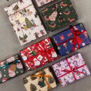 Blandade julklappspaket inslagna i färgglatt, festligt papper med motiv som tomte, renar, granar och band, perfekta för julklappsutdelning och firande.