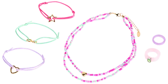 Sæt med lyserød og hvid perlehalskæde, tre pastelfarvede elastikarmbånd med guldfarvede vedhæng og to pastelfarvede ringe. Sjovt, farverigt smykke til børn eller teenagere.
