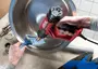 Rød og sort SKIL varmepistol med justerbar temperatur, spids dyse og ergonomisk håndtag, brugt med blå skraber på en metalskål.