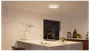 Moderne køkken med rund, indbygget LED-loftlampe. Hvid køkkenø med vask, minimalistisk dekoration og trædetaljer. Lampen giver klart, jævnt lys.