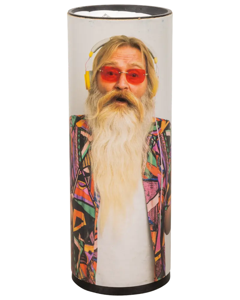 Cylindrisk højttaler med trykt design af en person iført farverig, geometrisk jakke, hvid T-shirt og gule hovedtelefoner. Ansigtet er sløret af hensyn til privatliv.