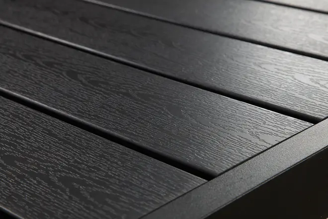 Närbild av svart utomhusbord med träådrad yta och ribbdesign, matt finish och robust rektangulär ram, perfekt för uteplats eller trädgård.