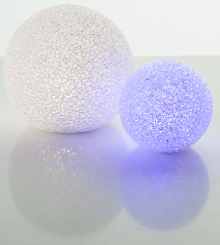 Set med två sfäriska LED-dekorationslampor med kristalliknande, texturerad yta. En lyser vitt, den andra blått. Perfekt för modern heminredning eller fest.