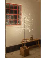 Konstgjort träd med varmvita LED-lampor på nakna grenar, placerat i en flätad korg. Passar för inomhus- eller skyddad utomhusdekoration, ger mysig stämning.