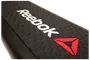 Sort Reebok stepbænk med skridsikker, nopret overflade, hvidt Reebok-logo og rød trekantet emblem. Robust plast, ideel til aerobic og steptræning.
