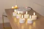Sæt med seks batteridrevne LED fyrfadslys med hvide baser og realistisk flammeeffekt, placeret på en træoverflade. Sikker dekoration eller stemningsbelysning.