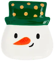 Keramiktallrik formad som en snögubbes ansikte med grön hatt och gula prickar, svarta ögon, orange morotsnäsa och ett litet leende. Festlig design för julen.