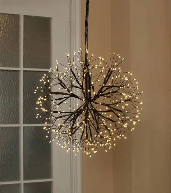 Hængende dekorativ lampe med sort grenlignende stel og varme hvide LED-spidser, der danner en rund mælkebøtte-lignende lysekrone.