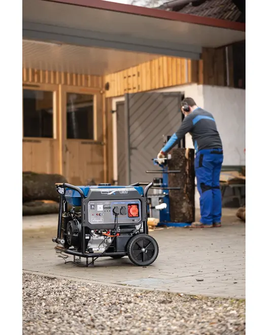 Bærbar generator med hjul og håndtag, flere strømudtag og kontrolpanel. Robust metalramme, velegnet til udendørs eller værkstedsbrug, sikrer pålidelig nødstrømforsyning.