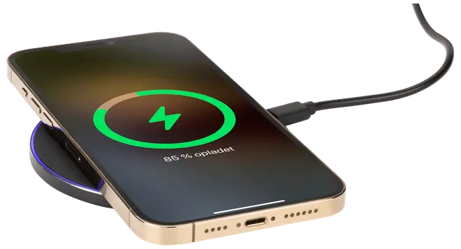 Guldfärgad smartphone på svart trådlös laddningsplatta, ansluten med USB-kabel. Skärmen visar laddningsstatus på 85%. Elegant design med rundade kanter och synlig laddningsport.