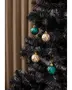 Sæt med fire facetslebne julekugler, to guld og to grønne, med skinnende geometrisk mønster, hængende på et sort kunstigt juletræ med guldsnor.