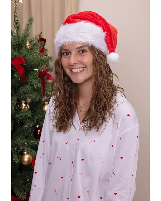 Hvid langærmet pyjamasskjorte med røde hjerter og slikstokke, knaplukning foran. Festligt design til jul. Modellen bærer også en rød og hvid nissehue.