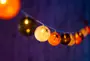 Ljusslinga med Halloween-tema, runda lampor i orange, svart och vitt, vissa med spindelmönster. Passar för festlig dekoration inomhus eller utomhus.