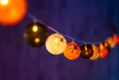 Ljusslinga med Halloween-tema, runda lampor i orange, svart och vitt, vissa med spindelmönster. Passar för festlig dekoration inomhus eller utomhus.