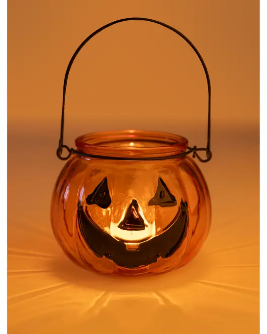 Orange glaslanterne formet som et græskar med sort græskarsmil, metalhank og tændt lys indeni. Ideel til Halloween dekoration eller som lysestage.