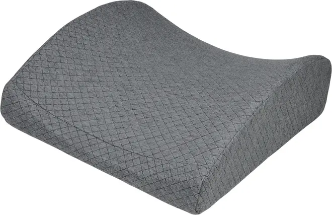 Grå quiltet kilepude med buet top og skrå sider, designet til støtte under ben eller knæ.