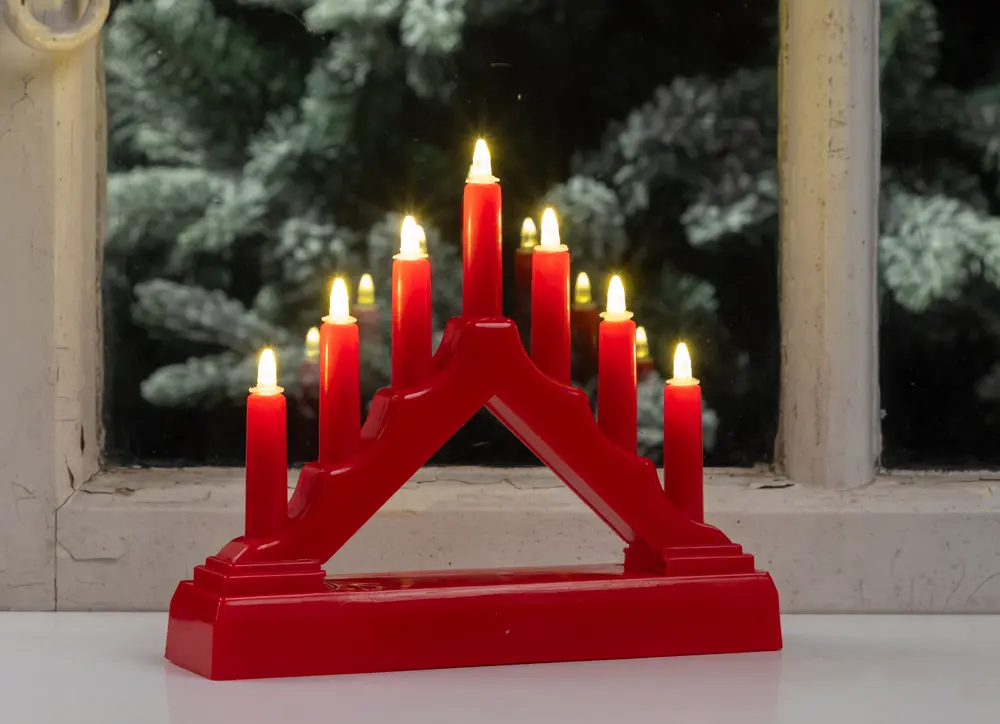 A red, triangular candle holder with seven electric candles arranged in a stepped pattern. Each candle has a small, flame-shaped bulb that emits a warm yellow light. The base is wide and sturdy, providing stability for display on a flat surface. The design is simple and festive, suitable for holiday decoration.