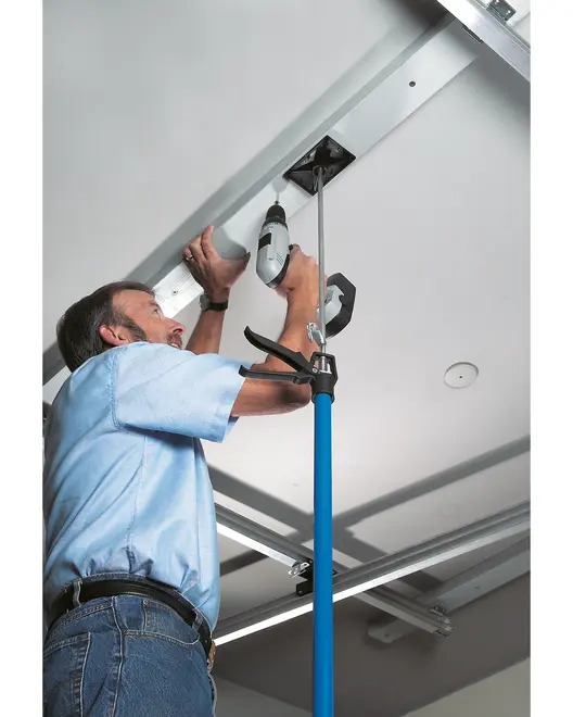 Blå teleskopstödstång med justerbar klämma, används för att hålla föremål på plats vid installation eller reparation, perfekt för arbete ovanför huvudet.