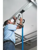 Blå teleskopstøttestang med justerbar klemme, bruges til at holde genstande på plads under installation eller reparation, ideel til arbejde over hovedet som montering af loftbeslag.