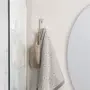 Væghængt metalkrog med en beige netpose og et gråt håndklæde med sildebensmønster. Perfekt til badeværelset for organiseret opbevaring af håndklæder og tilbehør.