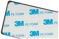 Rektangulär självhäftande dyna med vit yta, blå "3M PE FOAM"-text och svart kant. Används för montering eller fastsättning, dubbelsidig skumtejp.