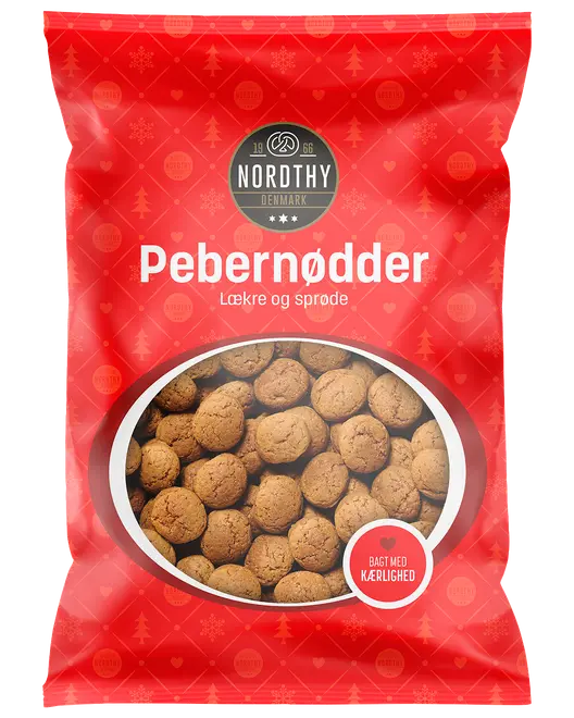 Rød pose Nordthy Pebernødder med små, runde, brune peberkager. Posens vindue viser indholdet. Tekst: Lækre og sprøde, bagt med kærlighed.