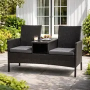 Sort bænksæt med indbygget bord står på fliser foran hus