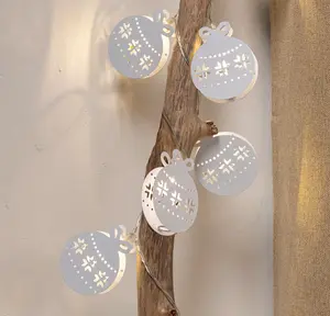 Ljusslinga med vita metallkulor, utskurna snöflingemönster och varmvita LED-lampor. Perfekt för jul- eller vinterdekoration i hemmet.