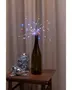 Vinflaske med flerfarvede LED-lyskæder arrangeret som fyrværkeri, brugt som dekorativt midtpunkt. Inkluderer glas med små diskokugler og stjerneformede pynt.
