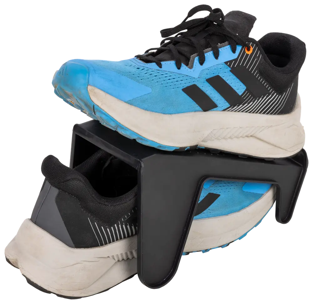 Blå og sorte sportssko placeret på en sort plastik sko-organisator, som holder én sko ovenover den anden for at spare plads og holde skoene organiseret.