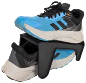 Blå og sorte sportssko placeret på en sort plastik sko-organisator, som holder én sko ovenover den anden for at spare plads og holde skoene organiseret.