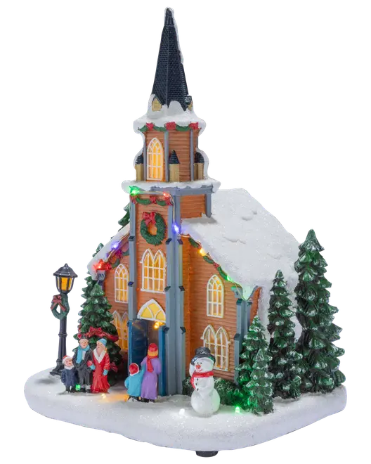 Snedækket julekirke med højt spir, oplyste vinduer, farverige lys, figurer, snemandsdekoration, grantræer og festlig krans.