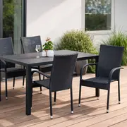 Udendørs spisesæt med fire sorte fletstole og et rektangulært sort bord. Bordpladen er lamelopdelt. Velegnet til terrasse. Inkluderer pynteplante og vinglas på bordet.