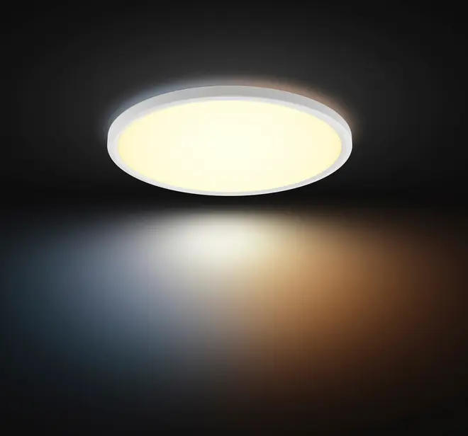 Rund LED-loftlampe med hvid ramme, udsender et varmt, diffust lys. Moderne, slankt design egnet til indendørs brug, giver jævn belysning i rummet.