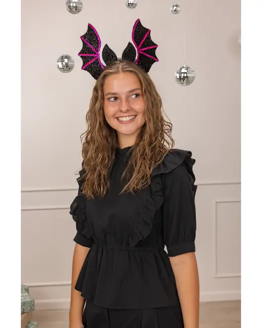 Svart hårband med glittriga fladdermusvingar och öron, dekorerat med rosa detaljer. Bärs med svart blus med volanger, puffärmar och markerad midja. Maskeradtillbehör för fest.