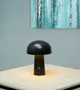 Moderne bordlampe med svampeform i mat sort finish, touch-strømknap på basen, udsender varmt lys nedad. Kompakt, minimalistisk design til skrivebord, natbord eller sidebord.