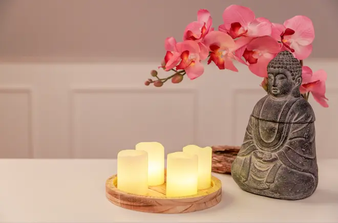Set med fyra LED-ljus på träbricka, en Buddha-staty i sten och rosa konstgjorda orkidéblommor, perfekt för heminredning eller avkopplande spa-känsla.