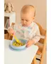 Babyhagesmæk med farverige regnbuer og skyer, vandtæt materiale, dækker bryst og skuldre, ideel til måltider. Vises på barn, der sidder ved bord og spiser pasta.