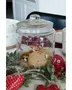Klar glasbeholder med låg, dekoreret med festlige hængende ornamenter, fyldt med småkager. Ideel til opbevaring af snacks, lufttæt lukning og julemotiv. Perfekt til køkken eller gave.