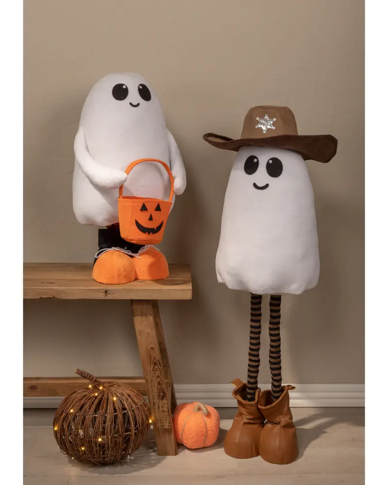 Two plush ghost figures with smiling faces. The ghost on the left has large black eyes, orange shoes, and holds an orange pumpkin-shaped bucket. The ghost on the right wears a brown cowboy hat with a silver sheriff star, has long striped legs, and brown boots. Both have a soft, white, rounded body. Decorative pumpkins and a lighted rattan ball are placed nearby.