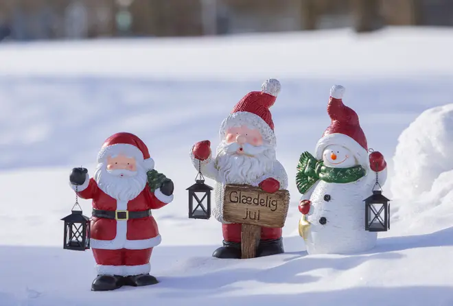 Tre julefigurer: julemand, julemand med skiltet 'Glædelig Jul' og en snemand, alle med lanterner til vinterdekoration.