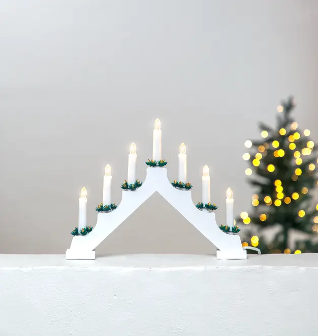 Hvid elektrisk lysestage i træ med syv LED-lys, hver pyntet med grønne kranse. Velegnet til vindueskarme eller juleudsmykning. Ledning ses ved bunden.