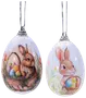 Två äggformade hängprydnader med målade kaniner och korgar fyllda med färgglada påskägg, dekorerade med vårblommor och silverfärgade upphängningsöglor.