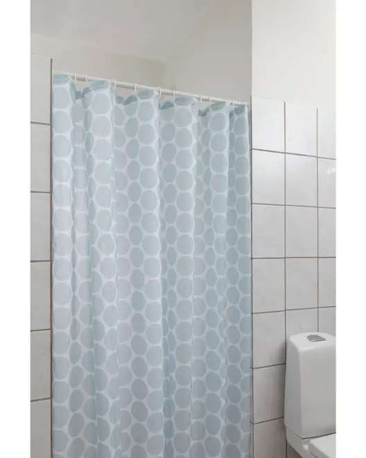 Ljusblå duschdraperi med stora vita prickar, tillverkad av vattentätt tyg, hänger på vita plastringar, passar standardbadkar eller duschar.