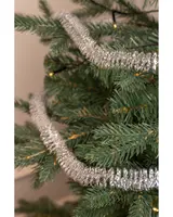 Silverglittrande girlang lindad runt konstgjorda gröna julgransgrenar, ger ett festligt och skimrande intryck. Perfekt för juldekoration, lätt att hänga upp.
